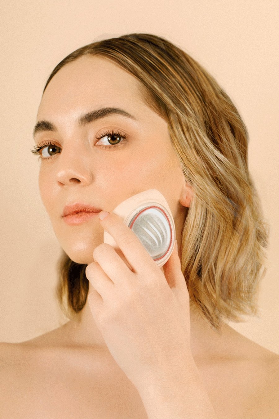A young woman with clean face holding a LED Light Therapy device