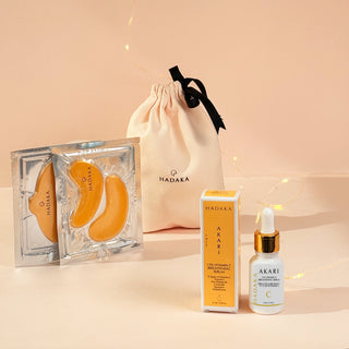 Brightening skincare products from the BRIGHT EDIT including Vitamin C Serum, Eye Mask, Lip Mask and suede pouch with 'HADAKA' branding on a beige background.