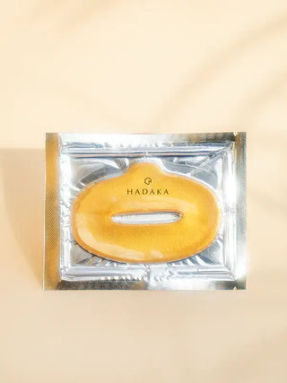 Gold hydrating lip mask in clear packaging on neutral background